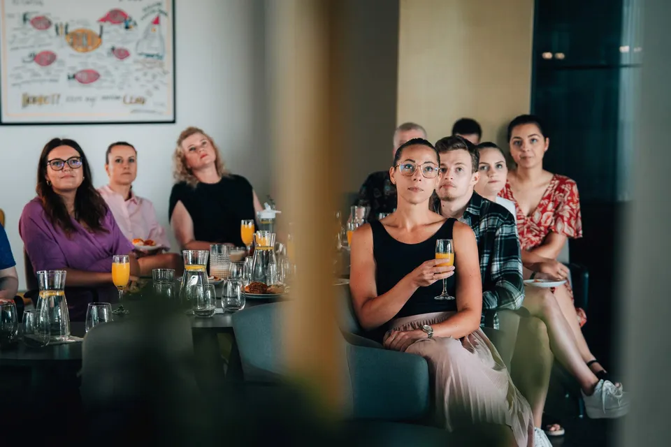 Účastnice firemní akce sledují program s drinkem v ruce